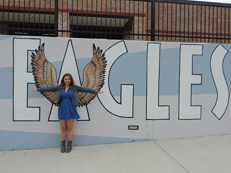 Staff member, Brittany Rodi, poses in front of the mural with War Eagle pride. 