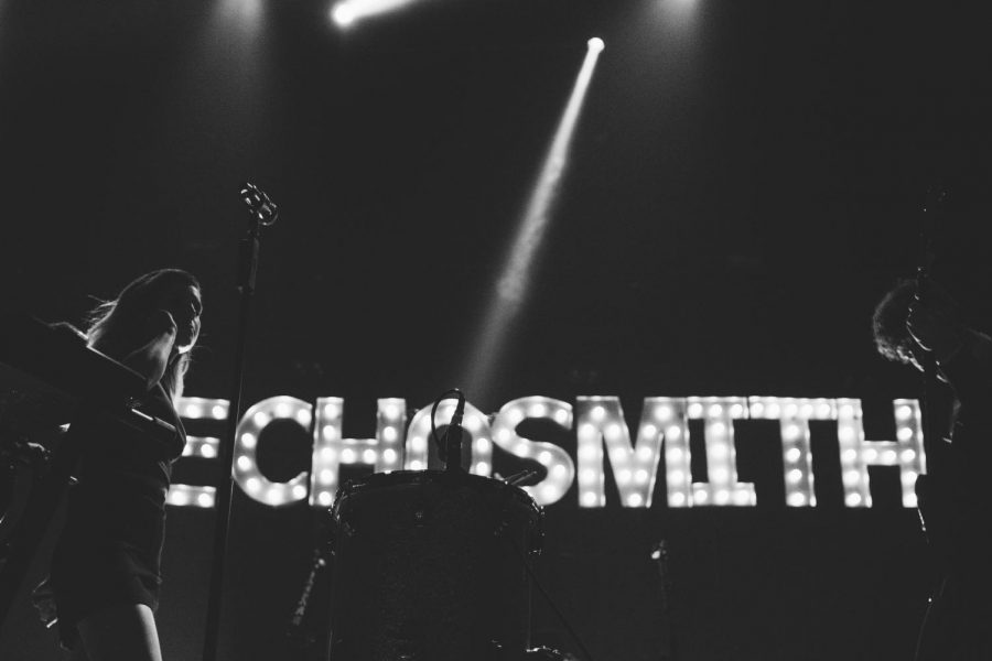 A performance by the band of siblings, Echosmith, shows their titled name flashing in the backdrop of the stage. (via Flickr under Creative Commons license).