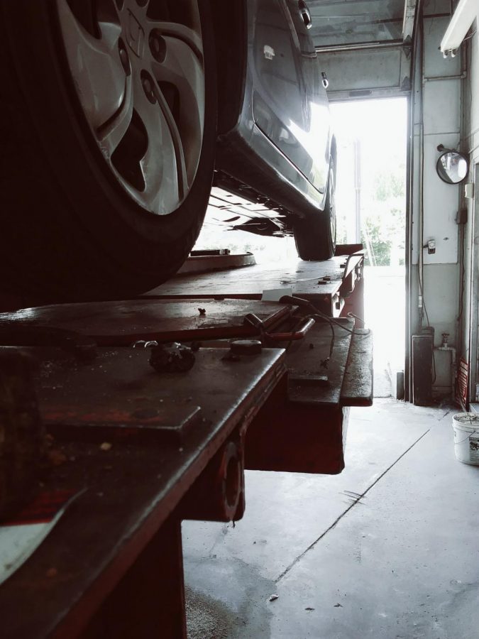 A Honda odyssey waits on the car lift for a tire alignment. 