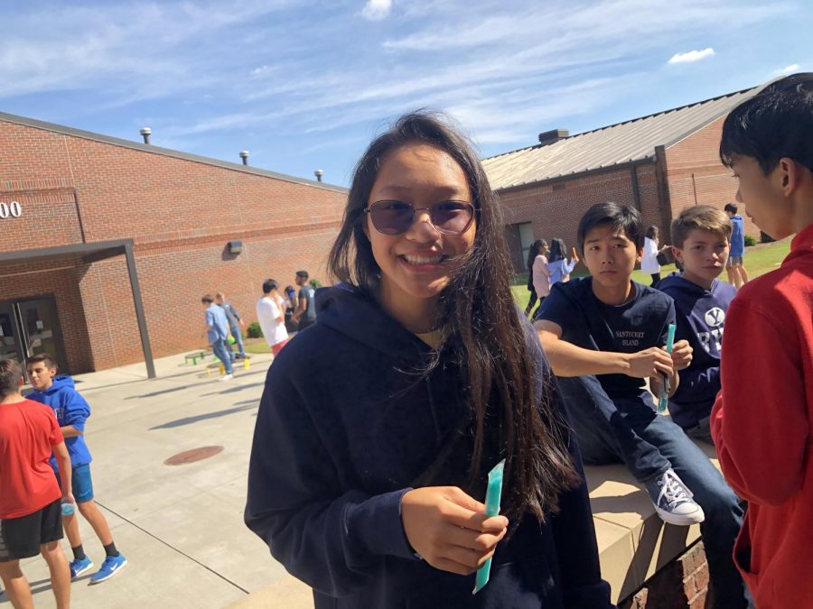 Tailgate with friends. Freshman Katelyn Kwak cools down with her popsicle underneath the warm sun. Faculty members passed out these sweet treats to students, eager to kickoff the  tailgate. 