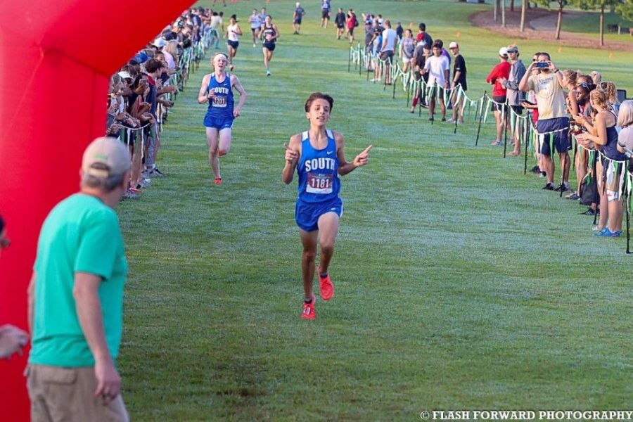 Boys+varsity+meet.+Junior+Ben+Bergey+leaps+to+the+finish%2C+leaving+Nate+only+a+few+seconds+behind.+Bergey+excitedly+pointed+his+fingers+up%2C+and+showed+the+sign+for+number+1+milliseconds+before+he+crossed+the+line.