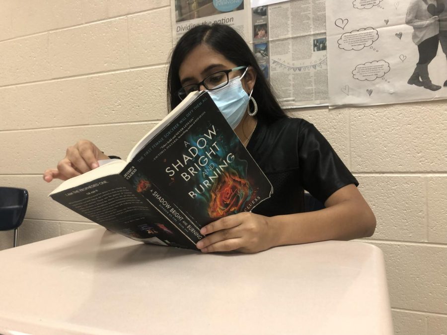 Rising from the ashes of life. (Pictured above) Senior Shree Delwadia is reading an intricate novel, A Shadow Bright and Burning, which features a variety of characters such as sorcerers, magicians, and demons. One of the best scenes from the book included the challenges that Hernietta faced to save her friend, Rook.