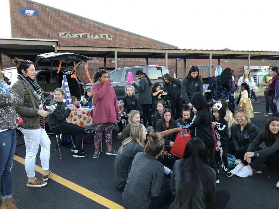 Cheering for candy. The Varsity Cheerleading team huddle together as hand out candy during the chilly evening. At this trunk, the children also eagerly waited to get their face painted with colorful designs.