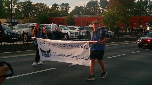Senior students carry the banner at the front of South's 2025 Homecoming Parade. (The Bird Feed Staff)